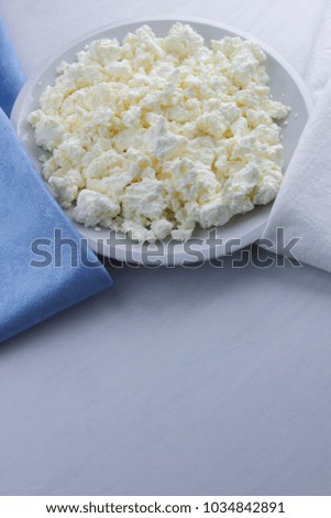 Cheese, cottage cheese on a white plate, fresh cottage cheese on a white and blue napkin, dairy product on a white background, healthy food, French breakfast, top view, goat curd in minimalist style