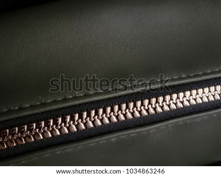 Zipper on a leather jacket or bag. Close-up photo of textured material. Casual clothing detail.
