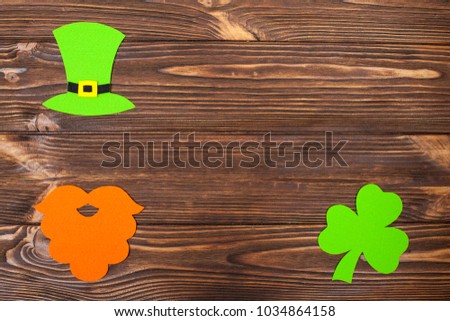St. Patrick's Day theme colorful horizontal banner. Green leprechaun hat, orange beard and shamrock leaves on brown wooden background with copy space. Felt craft elements for greeting card.