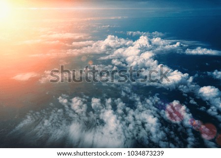 Sunrise above fluffy clouds, top view from airplane window, dramatic atmosphere landscape, toned