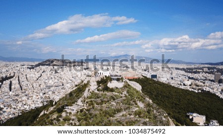 Aerial birds eye view photo taken by drone of Lycabettus hill and iconic Saint George chapel on top with beautiful scattered clouds and blue sky, Athens historic center, Attica, Greece