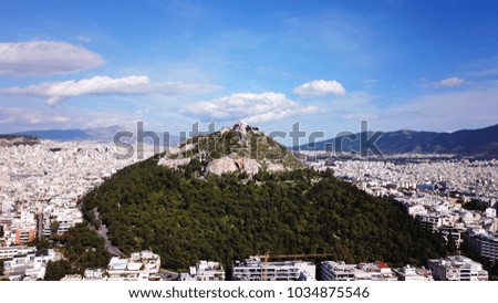 Aerial birds eye view photo taken by drone of Lycabettus hill and iconic Saint George chapel on top with beautiful scattered clouds and blue sky,  historic center, Attica, Greece