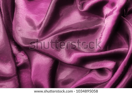 Smooth wavy purple satin fabric. drapery texture. Satin background.
