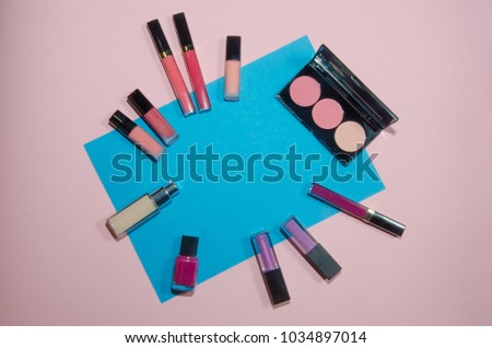 Red, pink and violet lipsticks. Rouge palettes, concealer and nail polish. Decorative cosmetics on blue and pink background. Top view, flatlay. Copyplace. Concept of color.