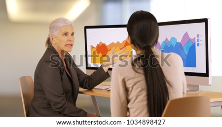 Two businesswomen discuss graphs