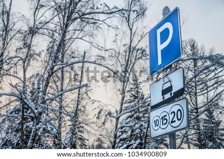 A closeup of a toll road street sign on the background of winter trees