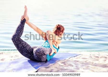 Yoga girl practicing laying stretching exercises on the river bank