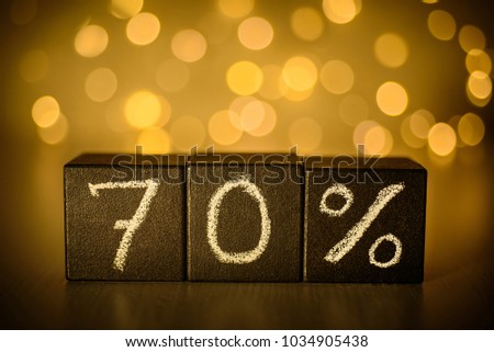 70% sign chalk written on  black cubes on blurred bokeh background