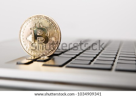 Golden Bitcoin - New virtual money on notebook. A visual representation of digital cryptocurrencies. Bitcoin are fully dematerialized and decentralized electronic currencies. Shallow depth of field.