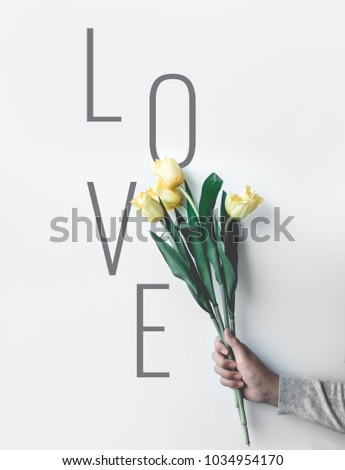 Love text with female holding  yellow tulip on white studio background.hipster, nature,fashion concepts ideas