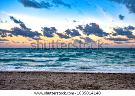 Picture of the sunset at Miami Beach, showing the sea, a cloudy and colorful sky, and ships at the background