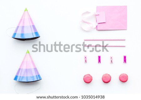 Birthday party accessories. Party hat, sweets, paper bag for gift on white background top view copy space pattern