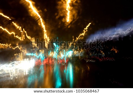 De focused image of rain falling on the road, looking out the window. Rain drops on window, rainy weather in the Montreal. Blurred car lights, long exposure photo of traffic. Wet asphalt.