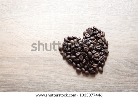 Heart shaped roasted coffee beans on wooden background.