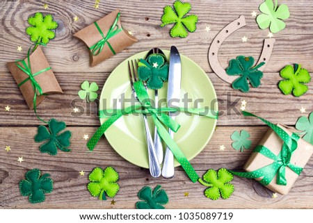Festive table setting for St.Patrick's day with cutlery and lucky symbols on wooden table. Top view.