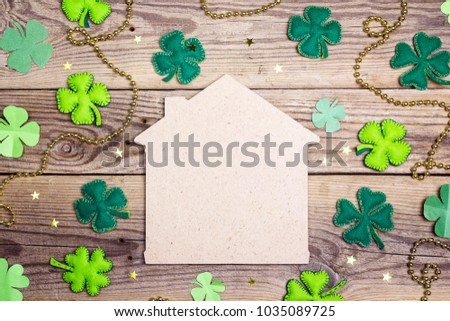 Lucky home symbol with four-leaf clover on wooden background. Copy space. St.Patrick's day holiday symbol. 