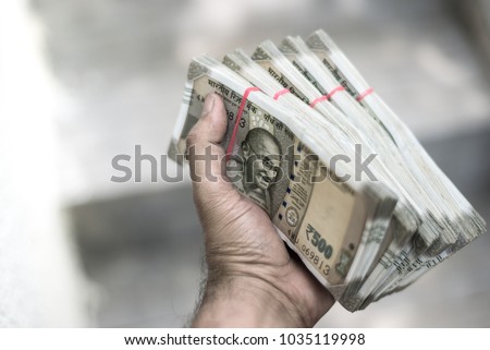Close up of a male hand holding stack of Indian Rupee notes. Cash transaction with new Indian currency notes. Royalty-Free Stock Photo #1035119998