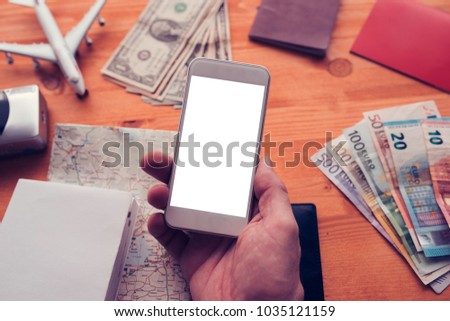 Travel planning and booking app for mobile phone. Man holding smartphone with blank screen as mock up copy space for text or graphics related to holiday vacation journey trip.