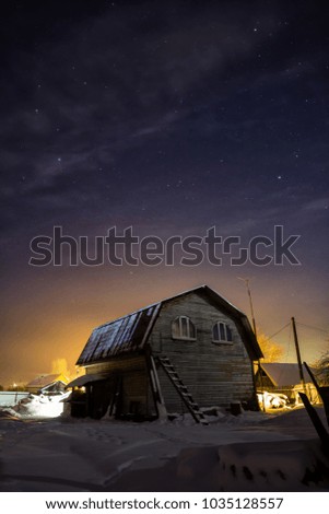 House in the Russian village of winter and frosty night. Starry the sky over head.