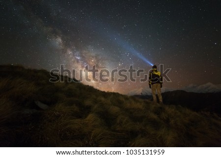Landscape with the Milky Way. The night sky with stars and the silhouette of a happy man standing on a mountain.