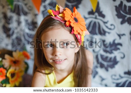 a beautiful girl in a yellow dress sits in autumn scenery: bright flags, pumpkins, flowers, apples have fun and rejoice