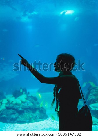 Girl watching fish through the glass in Oceanarium.