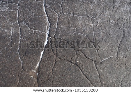 cracks on the asphalt sprinkled with snow