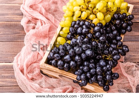 Picture of black grape in wooden box with pink cloth