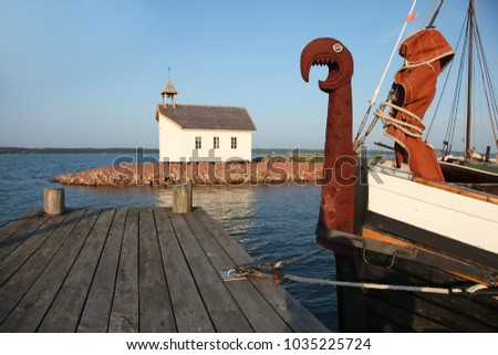Old viking boat and white chapel in shipyard in Marienhamn on Aland islands Royalty-Free Stock Photo #1035225724