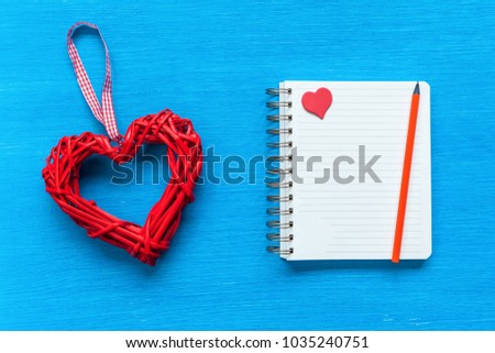 Notepad with multi-colored hearts and a pen lay on a table. Notepad with hearts.