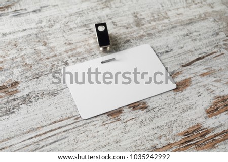 Blank plastic badge. Template for ID. White id card on wooden background. Mock-up for branding identity.