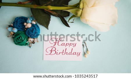 greeting card, White rose, earrings and brooch on a blue background the inscription "happy birthday"