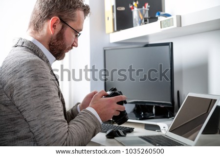 Photographer in home office working with laptop computer and looking at camera