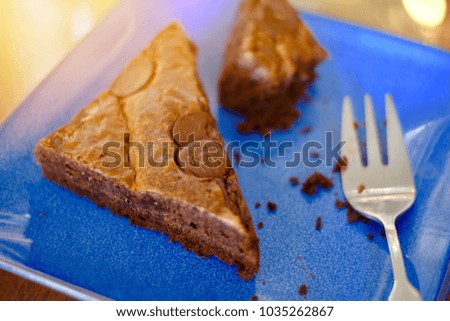 Blur picture of two piece of brownies and small fork on blue plate with space for your text and design. One of it was eaten. Concept be used for present bakery in coffee shop and bakery shop business.