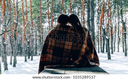 A loving young couple is resting in the mountains in a snow-covered forest. concept of joint rest