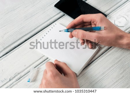 man writes in an empty notebook on the desktop