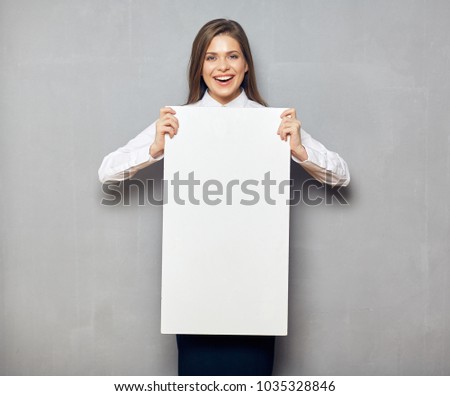young businesswoman holding big white board for advertising signs. Gray wall background.