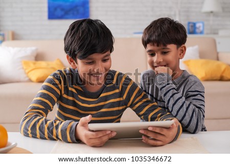 Two Indian excited brothers playing game on digital tablet
