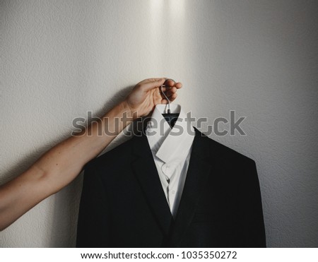 Man holds in his arms peg with black jacket and white shirt