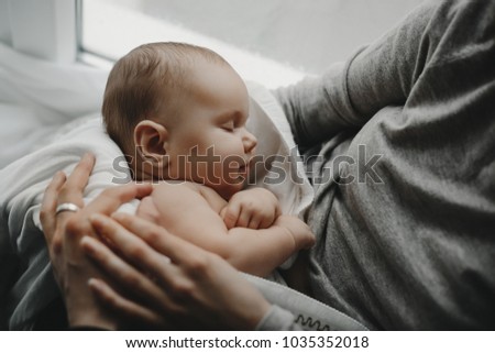Charming newborn boy sleeps on mother's arms Royalty-Free Stock Photo #1035352018