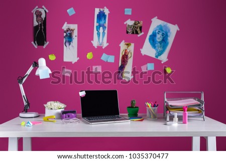 laptop with blank screen and office supplies at fashion designer workplace