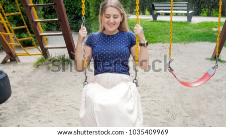 Portrait of smiling woman on swing at park