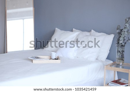 Wooden tray with coffee and interior decor on the bed with white linen