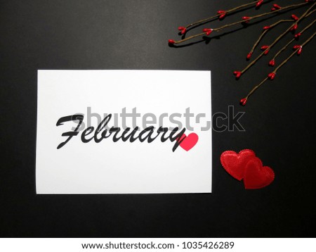 February sign on a black background with red hearts and twigs on the side