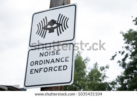 Close up on a Noise Ordinance Enforced sign with a symbol of person covering ears, posted in a residential neighborhood