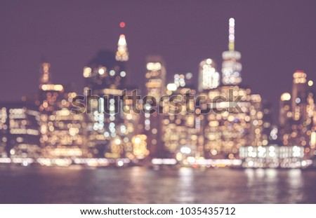 Blurred retro toned picture of Manhattan skyline at night, abstract urban background, New York City, USA.