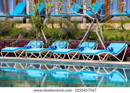 Deck chairs in tropical garden near swimming pool on the beach in island Bali, Indonesia