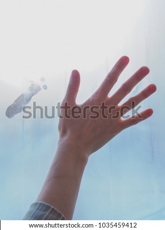 Beautiful female hand on misty glass.