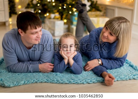 Young family on a blue plaid near Christmas tree