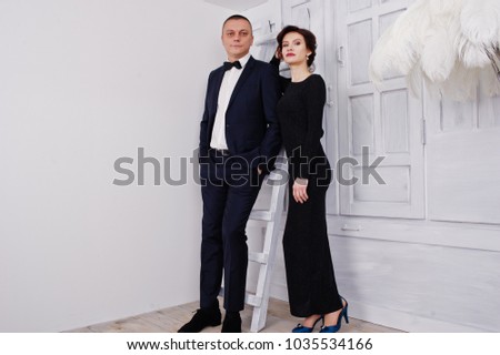 Elegance woman in black evening dress with man in suit posed on studio. Duet couple of two.